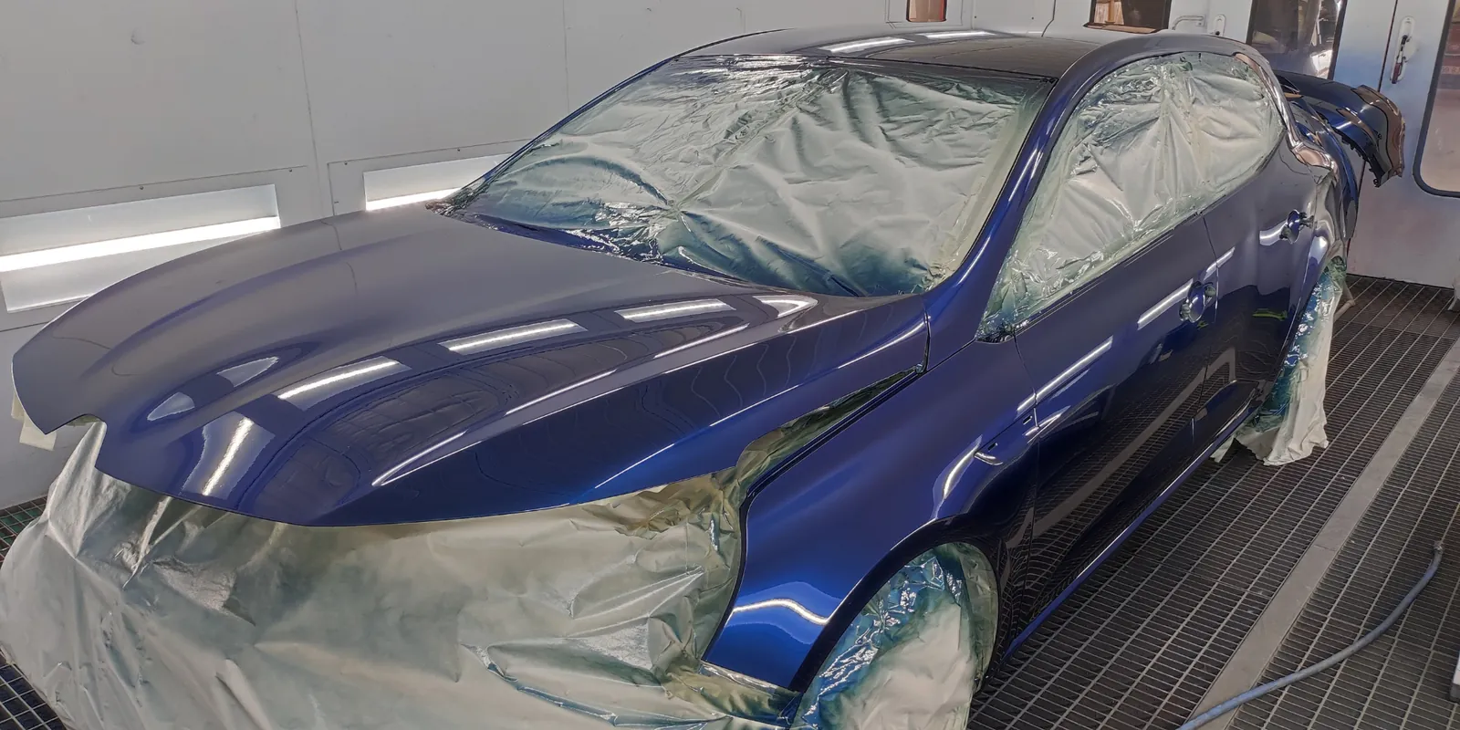 Vehículo azul enmascarado dentro de la cabina de pintura